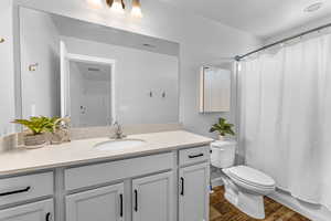 Bathroom with a shower with curtain, vanity, toilet, and wood-type flooring