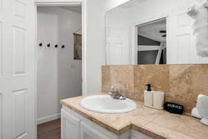 Bathroom featuring decorative backsplash, hardwood / wood-style floors, vanity, and ceiling fan