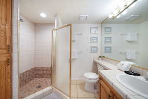 Bathroom with vanity, a shower with door, tile patterned floors, toilet, and a textured ceiling