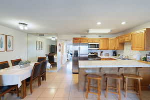 Kitchen with a kitchen breakfast bar, tile countertops, and stainless steel appliances