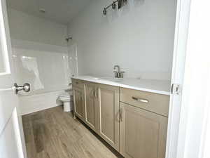 Full bathroom featuring vanity, a textured ceiling,  shower combination, wood-type flooring, and toilet