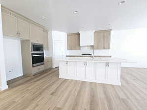 Kitchen with sink, a kitchen island with sink, stainless steel appliances, light hardwood / wood-style floors, and decorative backsplash