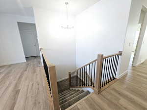 Staircase featuring a chandelier and hardwood / wood-style floors