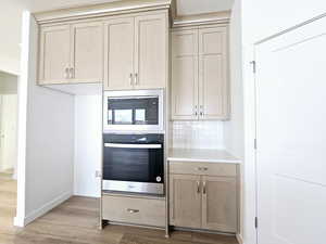 Kitchen featuring light hardwood / wood-style floors, appliances with stainless steel finishes, and tasteful backsplash