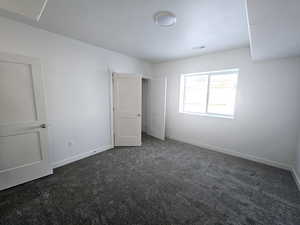 Unfurnished bedroom featuring dark carpet