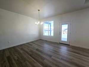 Unfurnished dining area featuring dark hardwood / wood-style flooring and a chandelier