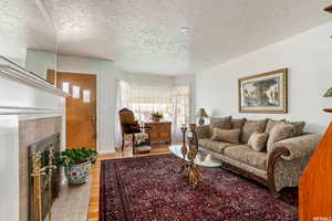 Living room with a tile fireplace, hardwood / wood-style floors, and a textured ceiling