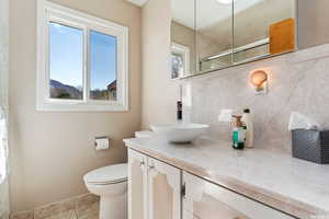 Bathroom with tile patterned flooring, vanity, toilet, and a wealth of natural light