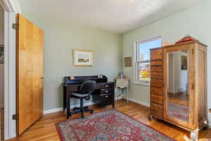 Home office with light hardwood / wood-style flooring and a textured ceiling