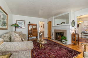 Living room with a tile fireplace, ceiling fan, hardwood / wood-style floors, and a textured ceiling