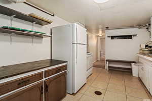 Kitchen with white cabinets, white appliances, and light tile patterned floors