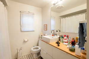 Bathroom with a textured ceiling, vanity, and toilet