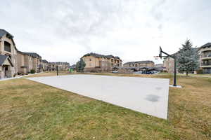 View of basketball court featuring a playground and a lawn