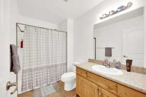 Bathroom featuring tile patterned floors, curtained shower, vanity, and toilet