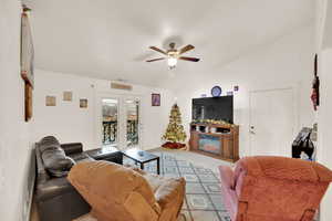 Living room with light colored carpet, ceiling fan, and lofted ceiling