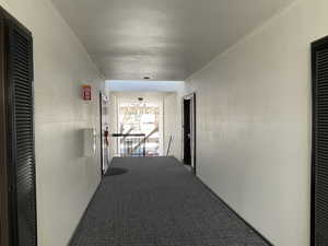 Corridor featuring carpet and a textured ceiling