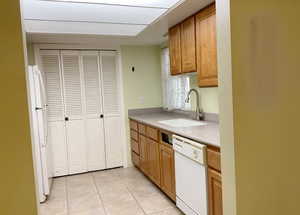 Kitchen with light tile patterned floors, white appliances, and sink