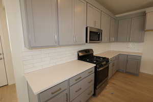 Kitchen featuring upgraded backsplash, quartz countertops, painted cabinets with gold handles