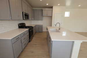 Kitchen with upgrades quartz countertops, tile backsplash, composite sink and laminate flooring