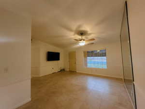 Empty room featuring ceiling fan and lofted ceiling