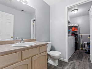 Bathroom with hardwood / wood-style floors, a textured ceiling, toilet, vanity, and washer and dryer