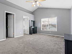 Unfurnished bedroom with ceiling fan, light colored carpet, and lofted ceiling