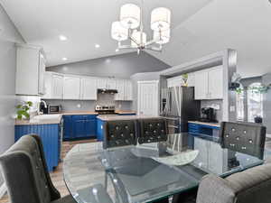 Kitchen with appliances with stainless steel finishes, sink, blue cabinetry, light hardwood / wood-style flooring, and white cabinetry