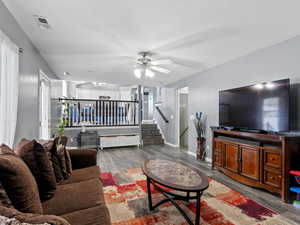 Living room with ceiling fan, dark wood-type flooring, and a textured ceiling