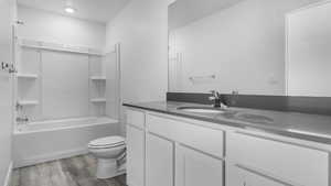 Full bathroom with toilet, vanity, shower / bath combination, and hardwood / wood-style flooring