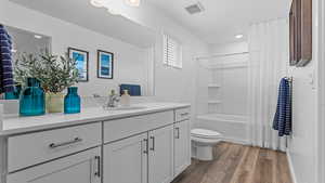 Full bathroom with wood-type flooring, vanity, toilet, and shower / bath combo