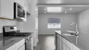 Kitchen with light hardwood / wood-style floors, sink, white cabinetry, and stainless steel appliances