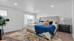 Bedroom with a textured ceiling and dark colored carpet