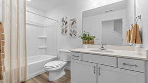 Full bathroom with toilet, vanity, shower / bath combination, and hardwood / wood-style flooring