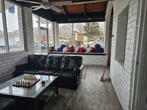 Sunroom featuring beam ceiling, ceiling fan, and wooden ceiling