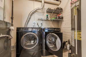 Laundry area featuring light tile patterned floors, washer and dryer, and gas water heater