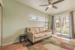 Living room with plenty of natural light, light hardwood / wood-style floors, lofted ceiling, and ceiling fan