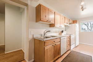 Kitchen featuring white appliances, sink, light brown cabinetry, and light hardwood / wood-style flooring