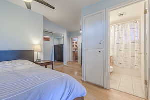 Bedroom with ensuite bathroom, ceiling fan, a closet, and light hardwood / wood-style flooring