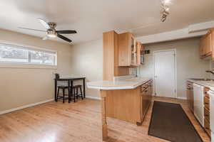 Kitchen featuring dishwasher, sink, light hardwood / wood-style flooring, kitchen peninsula, and a kitchen bar