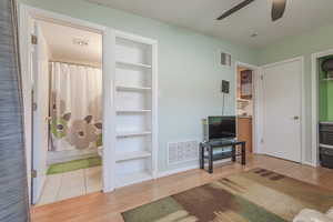 Living room featuring built in shelves, light wood-type flooring, and ceiling fan