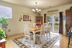 Dining space with light hardwood / wood-style floors and a notable chandelier