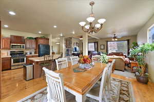 Dining room with light hardwood / wood-style flooring and ceiling fan with notable chandelier