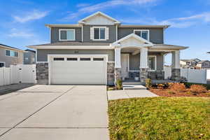 Craftsman-style house with covered porch, a garage, and a front lawn