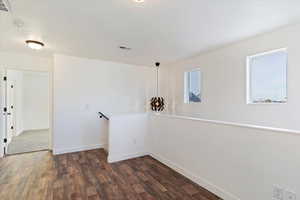 Unfurnished room with a healthy amount of sunlight and dark wood-type flooring