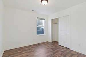 Unfurnished bedroom featuring a closet and dark hardwood / wood-style flooring