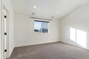 Carpeted spare room with lofted ceiling