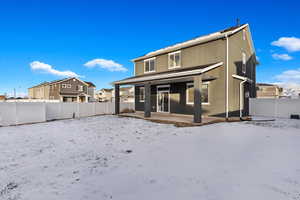 Snow covered back of property featuring a patio area