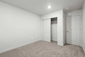 Unfurnished bedroom featuring light carpet and a closet