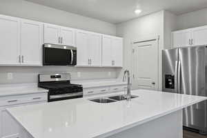 Kitchen featuring white cabinetry, sink, an island with sink, and appliances with stainless steel finishes