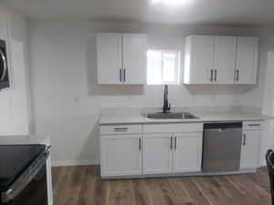 Kitchen with dark hardwood / wood-style flooring, sink, white cabinets, and appliances with stainless steel finishes